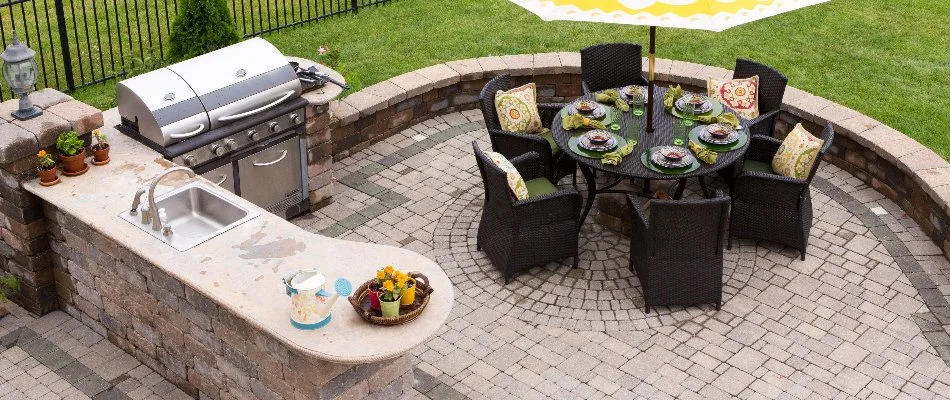 Patio in New Braunfels, TX, with an outdoor kitchen, seating wall, and dining area.