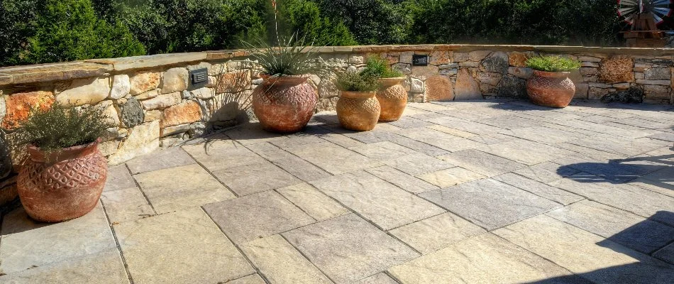 Paver patio in New Braunfels, TX, with seating wall and potted plants.