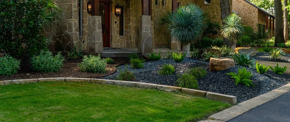 Green grass and neat landscape in Vintage Oaks, TX, with small shrubs.