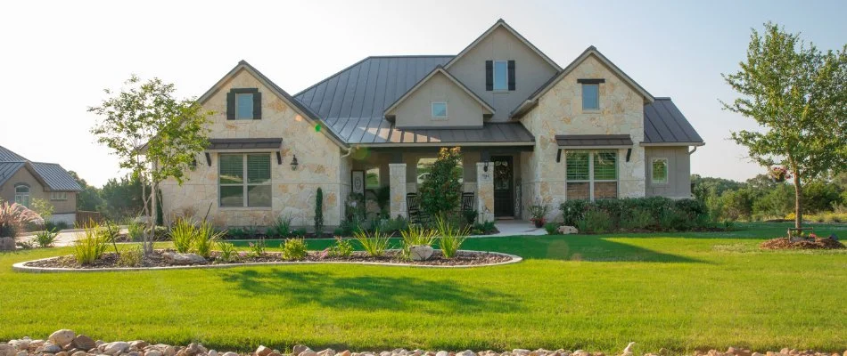 Healthy green lawn with plants near a house in Gruene, TX.