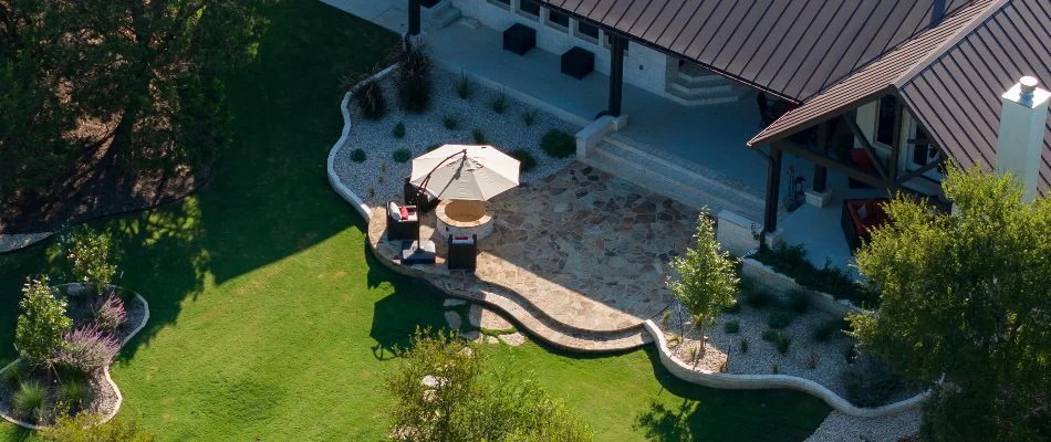 Outdoor living space in Oak Run, TX, with a patio, fire pit, green lawn, and landscaping.