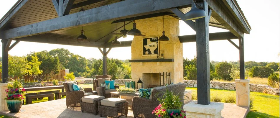 Pavilion in New Braunfels, TX, with an outdoor fireplace and some chairs. 