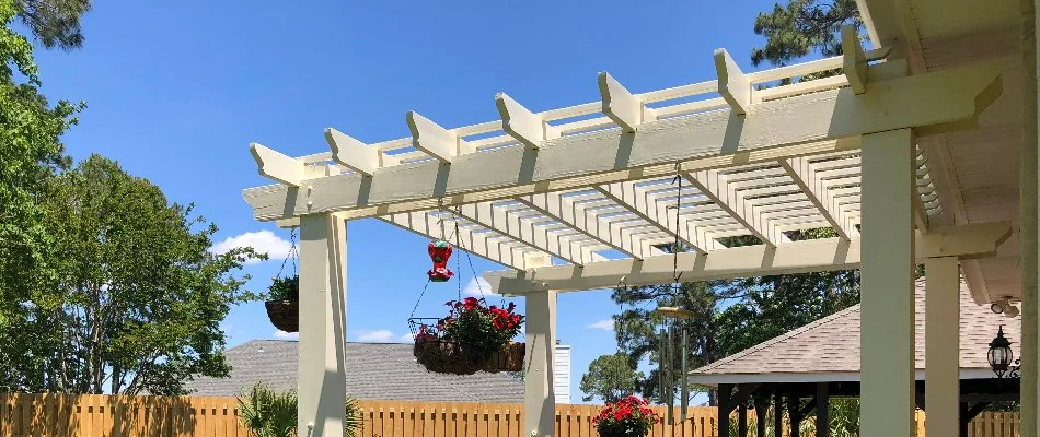 Wooden pergola in New Braunfels, TX, with hanging plants.